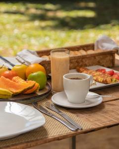 a table with a cup of coffee and a plate of fruit at Nativ Lodge and Spa in Mahébourg