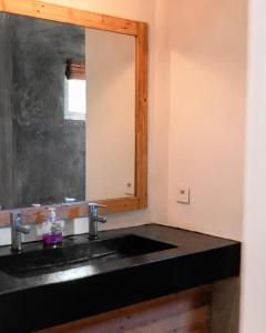 a bathroom with a black sink and a mirror at Nativ Lodge and Spa in Mahébourg