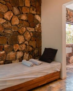 a bedroom with a stone wall and a bed with towels at Nativ Lodge and Spa in Mahébourg