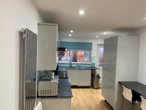 a kitchen with white cabinets and black counter tops at Corporate Large Modern 4 to 5 Bedroom House in Bishops Stortford