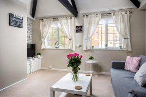 a living room with a couch and a table with flowers on it at Curb Properties - Super Apartment Moments From Town Centre in Cheltenham