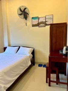 a bedroom with a bed and a fan and a table at T's House Motel in Ấp Bình Hưng