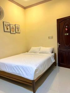 een slaapkamer met een bed met witte lakens bij T's House Motel in Ấp Bình Hưng