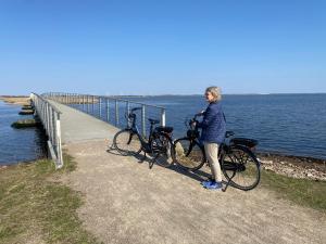 een vrouw die naast twee fietsen op een pier staat bij Søndervig Camping & Cottages in Søndervig