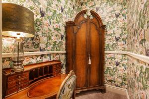 a room with a wooden cabinet and floral wallpaper at The Wynnstay Hotel, Oswestry, Shropshire in Oswestry