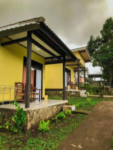 a yellow house with a porch and a bench at Achita Cottages in Senaru