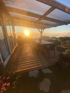 una terraza de madera con una mesa y la puesta de sol en el fondo en Chalet de Notre Dame, en Le Tampon