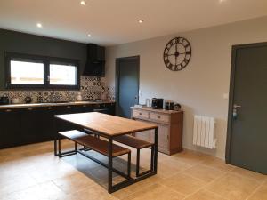 a kitchen with a table and a clock on the wall at Cosy Wood House in Laubressel