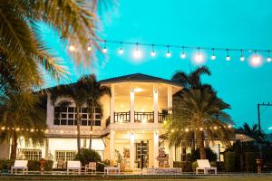 a large white house with lights and palm trees at ทรายทอง รีสอร์ท in Ban Pru Yai