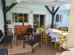una mesa de comedor y sillas en un porche con mesa y sillón en La villa Cocotiers, en La Saline-Les-Bains