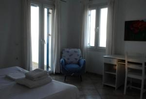 Schlafzimmer mit einem blauen Stuhl, einem Schreibtisch und einem Fenster in der Unterkunft Beach House in Tinos island in Kardhianí