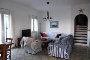 ein Wohnzimmer mit einem Sofa, Stühlen und einem Tisch in der Unterkunft Beach House in Tinos island in Kardhianí