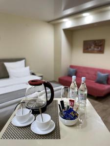 Central Hotel Gyumri في غيومري: طاولة مع غلاية شاي واكواب وقوارير ماء