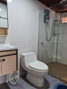 La salle de bains est pourvue d'une douche et de toilettes blanches. dans l'établissement Lampang Hideaway Guesthouse, à Lampang