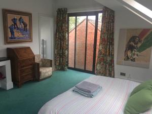 a bedroom with a bed and a chair and a window at Lake Street Studios in Oxford