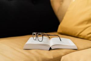un libro con un paio di occhiali seduto su un letto di Apart ENO a Stumm
