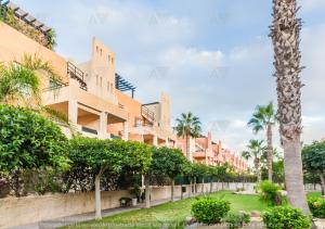 una fila de edificios de apartamentos con palmeras y arbustos en Duplex PARAISO VERA Playa PISCINA PRIVADA, en Vera