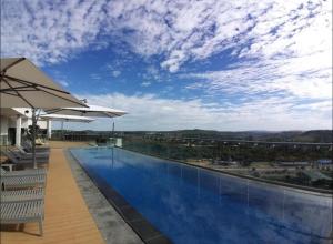 a large swimming pool with chairs and an umbrella at 418 Menlyn Maine Trilogy in Pretoria
