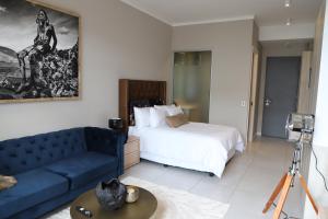 um quarto de hotel com uma cama e um sofá azul em 418 Menlyn Maine Trilogy em Pretoria