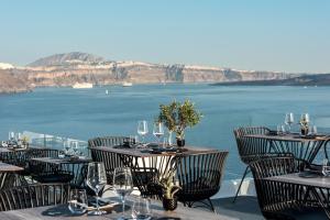 La Perla Villas and Suites - Adults Only في أويا: مطعم بطاولات وكراسي مطل على المحيط