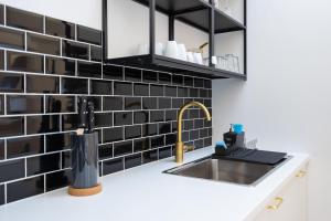 a kitchen with black tile and a sink at Stilvolle Dachgeschosswohnungen mit Balkon in Innenstadt Nähe in Vienna