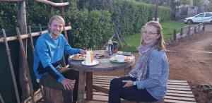 un hombre y una mujer sentados en una mesa con comida en Chocks Guest House, en Lejone