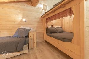 2 camas en una cabaña de madera con paredes de madera en Chalet Le Bois Joli en Bonneval-sur-Arc