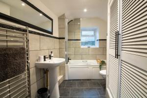 a bathroom with a sink and a tub and a toilet at Stylish and Modern Town Centre End-of Terrace Home in Newton Abbot