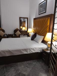 1 dormitorio con 1 cama, 2 lámparas y espejo en 1 Kanal Entire House with 4 Bedrooms, en Lahore