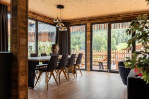 a dining room with a table and chairs and windows at Alpenchalets Biberwier Zugspitze by ALPS RESORTS in Biberwier