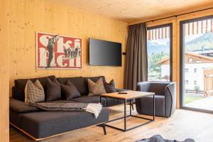 a living room with a couch and a tv on a wall at Alpenchalets Biberwier Zugspitze by ALPS RESORTS in Biberwier