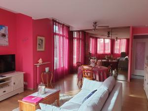 a living room with pink walls and a couch and a table at Appartement LA VIE EN ROSE in Périgueux