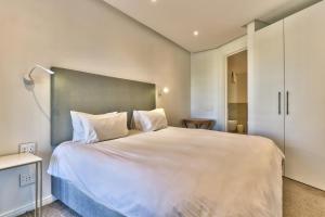a bedroom with a large white bed with white pillows at Two Bedroom Apartment - fully furnished and design in Va Marina Residential in Cape Town