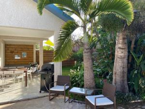 a patio with tables and chairs and palm trees at La villa Selah **** in Saint-Louis