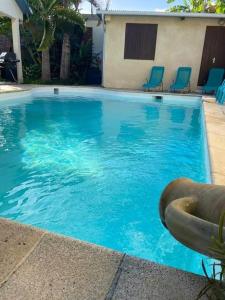 ein großer blauer Pool mit blauen Stühlen in der Unterkunft La villa Selah **** in Saint-Louis