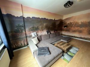 コトブスにあるCottbuser City Ferienwohnungのリビングルーム(灰色のソファ、絵画付)
