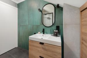 W łazience znajduje się biała umywalka i lustro. w obiekcie Zen Apartment by LoftAffair w Krakowie
