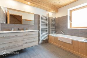 La salle de bains est pourvue d'une baignoire, d'un lavabo et d'un miroir. dans l'établissement Chalet Le Bois Joli, à Bonneval-sur-Arc