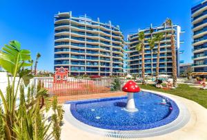 una piscina con fungo rosso di fronte a un edificio di Bennecke Velvet a Punta Prima