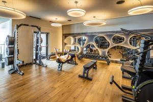 a gym with tread machines and a man laying on a bench in the middle at My Arbor - Plose Wellness Hotel in Bressanone