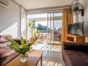 a living room with a couch and a tv at Apollonia Hotel Apartments in Paphos