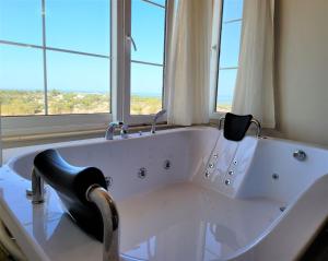 a large white bath tub in a room with windows at Patara Evleri in Patara