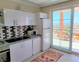 Patara Evleri في باتارا: مطبخ مع دواليب بيضاء وباب زجاجي منزلق كبير