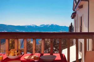 a table with a bowl of food on a balcony with mountains at CHARMANT T3 AVEC VUE SUR LA MONTAGNE in Font-Romeu-Odeillo-Via