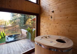 a wooden bathroom with a tub and a large window at PinusVillas Conference Lodge in Zheleznitsa