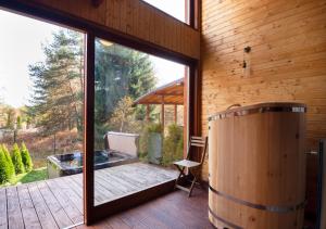 eine Holzterrasse mit einer großen Glastür und einem Fass in der Unterkunft PinusVillas Conference Lodge in Zheleznitsa