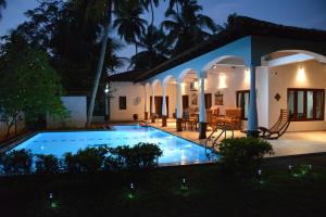 a villa with a swimming pool at night at Lucas in Bentota
