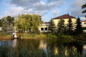 a woman sitting on a bridge over a lake in front of a house at Zacisze in Ulan