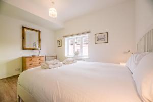 - une chambre avec un grand lit blanc et une fenêtre dans l'établissement 4 Ropers Court Lavenham, à Sudbury