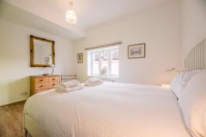 a bedroom with a large white bed and a window at 4 Ropers Court Lavenham in Sudbury